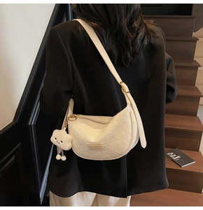 Close-up of white crescent Hobo bag with textured fabric and plush cloud charm