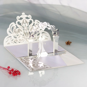 Macro detail of laser-cut 3D wedding card featuring white lace arch and silver bride silhouette