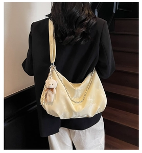 Detail of cream shoulder bag featuring silver chain and cute teddy bear plush charm