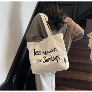 Detail of the cream canvas tote bag featuring less Mondays more Sundays embroidery