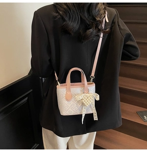 Detail of white jacquard bucket bag with pink leather trim and pearl heart pendant
