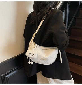 Detailed view of white dumpling bag with jacquard texture and plush cloud charm