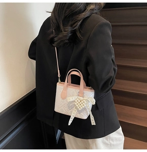 Detail of pink leather handbag with lace bow and pearl heart charm on female model