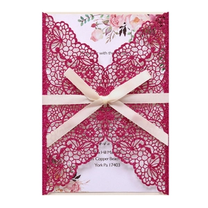 Macro detail of laser-cut butterfly invitation with pink glitter and white ribbon bow