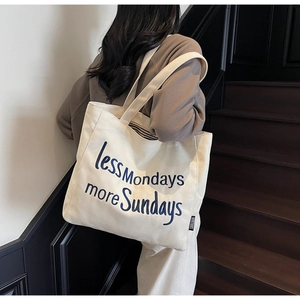 Detail of canvas tote bag with 'less Mondays more Sundays' embroidery on white fabric