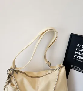 Detail of light yellow patent leather tote bag with silver chain and dual shoulder straps