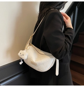 Close-up of white wrinkled leather dumpling bag with cloud plush charm and shoulder strap