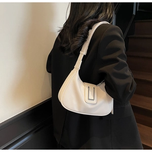 Detail view of white crescent shoulder bag with silver metal buckle on black blazer