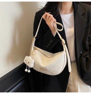 Detail of white moon-shaped hobo bag with textured surface and cute cloud plush charm