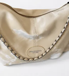 Close-up of cream leather shoulder bag with embossed fashion logo and chain strap