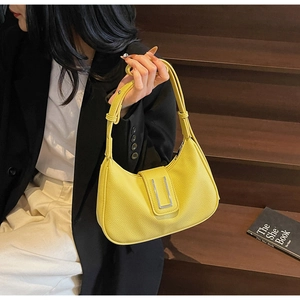 Detail of yellow lychee leather hobo bag with silver buckle worn by a model