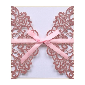 Elegant laser cut wedding invitation with rose gold glitter and a pink silk ribbon bow