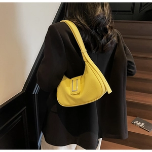 Chic yellow half-moon leather shoulder bag with silver buckle worn on a black blazer