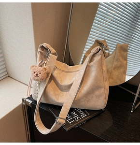 Detail der beigen Cord-Hobo-Tasche mit verstellbarem Gurt und süßem Plüschbären