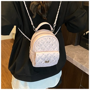 Rear view of a model wearing the pink quilted mini backpack with pearls and chain straps