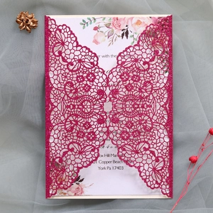 Detail of rose red laser-cut wedding invitation with hollow floral lace and glitter texture
