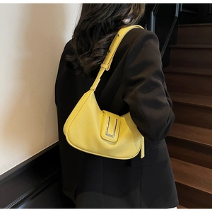 Detail of yellow lychee grain leather shoulder bag with a silver metal buckle accent