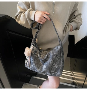 Detail der grauen Hobo-Tasche mit Gänseblümchenmuster und rosa Plüschbär-Anhänger