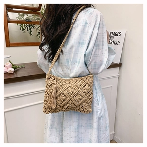 Close-up of woven diamond pattern and tassel detail on handmade straw shoulder bag