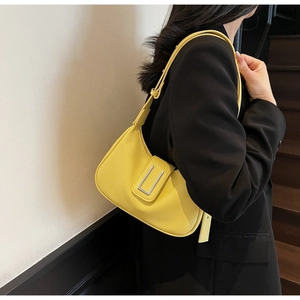 Detail of bright yellow leather hobo bag with silver buckle worn with a black blazer
