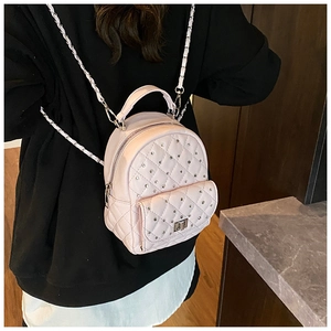 Close-up of pink quilted backpack with silver chain straps and rhinestone detail