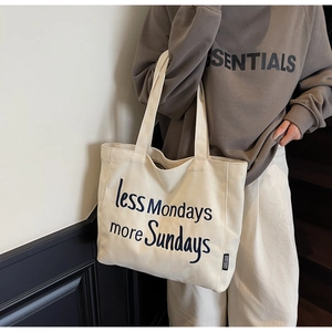 Close-up of beige canvas tote bag with less Mondays more Sundays embroidery detail