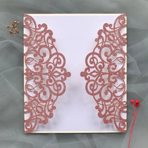 Detail of laser-cut rose gold glitter invitation with intricate vine patterns