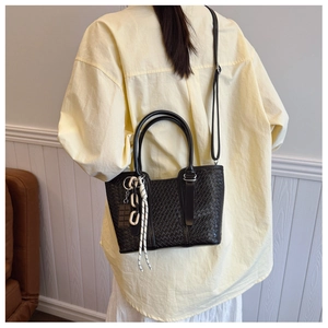 Détail du sac à main noir en cuir PU tressé avec breloque chocolat et bandoulière