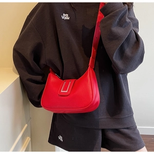 Detail of red crescent shoulder bag with lychee texture and silver metal buckle