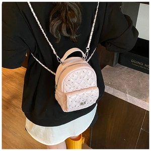 Detail view of pink quilted mini backpack featuring rhinestone studs and metal chain straps