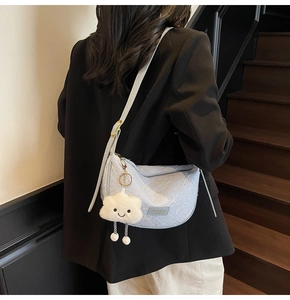 Detail of light blue crescent bag featuring white floral embroidery and cloud pendant