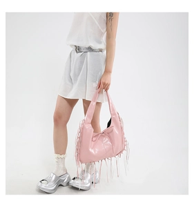 Close-up of pink Y2K shoulder bag with long fringe tassels and bow detail on a model