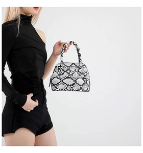 Close-up of black and white snakeskin shell bag with textured leather and dual handles