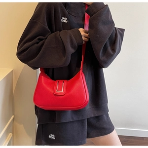 Détail d'un sac bandoulière en cuir grainé rouge avec boucle en U argentée sur mannequin
