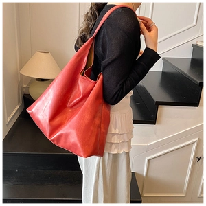 Close-up of a large red leather tote bag showing grainy texture and soft natural luster