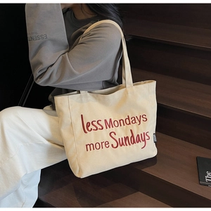 Detail of red Less Mondays More Sundays embroidery on off-white canvas tote bag