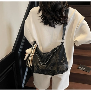 Detail of black marble textured shoulder bag with silver chain and plush bear charm