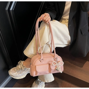 Detailed shot of a pink pebbled leather pillow bag with pearl heart pendant and pockets