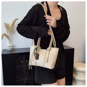 Détail du sac à main beige tressé avec breloque chocolat et bandoulière amovible
