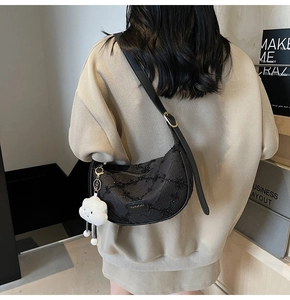 Close-up of black crescent dumpling bag with fine texture and white plush cloud charm