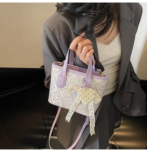 Detail view of light purple bucket bag featuring geometric embroidery and pearl heart charm