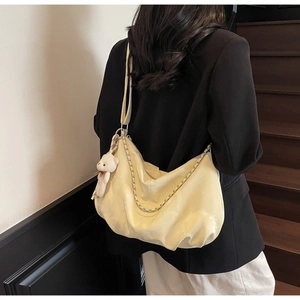 Detail of pale yellow PU leather hobo tote with metal chain and plush bear charm