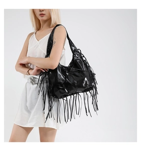 Detail of a black hobo shoulder bag with long fringes and shiny synthetic leather texture