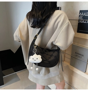 Detail of black dumpling bag with embroidery, leather strap and cloud charm accessory