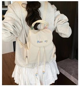 Close-up of cream nylon backpack featuring drawstring closure and MeaRey embroidery
