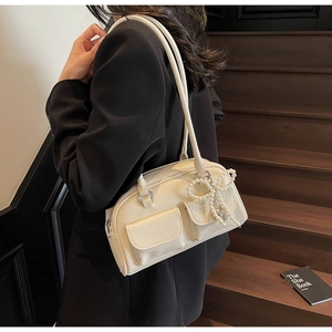 Detail of cream pillow shoulder bag featuring lychee texture and pearl bow charm