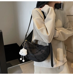 Detail view of black crescent dumpling bag with textured fabric and cloud charm