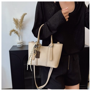 Détail du sac beige avec texture tissée, relief crocodile et breloques décoratives