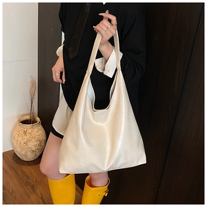 Cream white tote bag with glossy finish shown in a stylish over the shoulder carry view