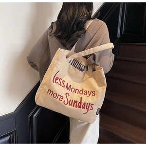Detail of red embroidery text on off-white canvas tote bag for casual daily use